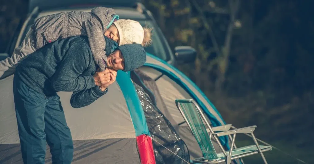 Family setting up a tent at a wooded campsite during a kid-friendly camping trip