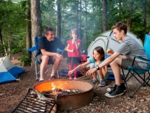 Kids around the campfire with Dad and a tent in the background